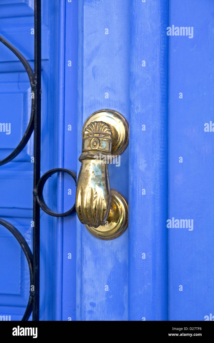 Türgriff aus Messing in Form einer Hand, auf blaue Tür mit schwarzem Schmiedeeisen Schmiedearbeiten Stockfoto