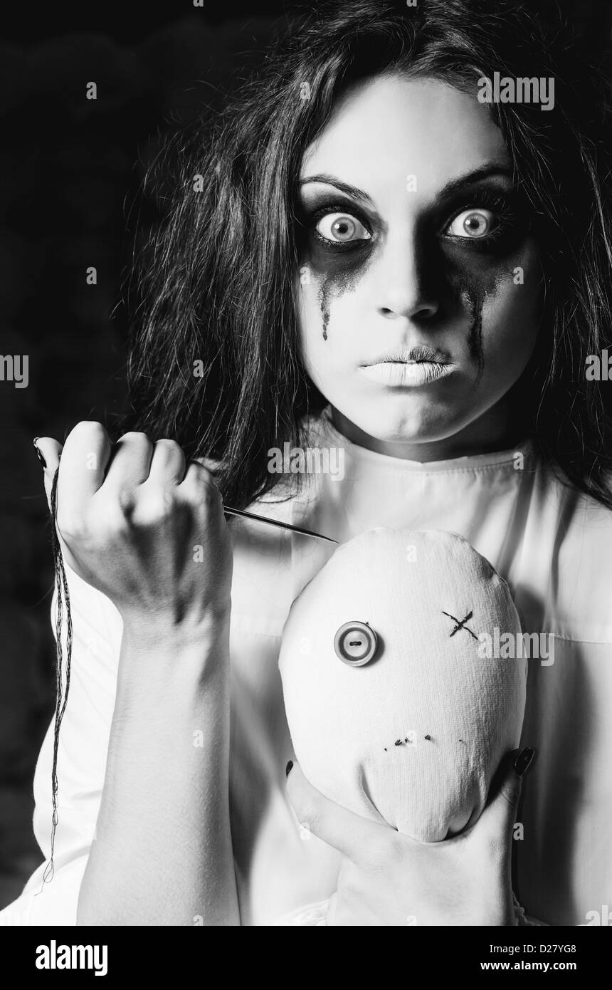 Horror-Szene: seltsame verrücktes Mädchen mit Puppe Mizzi und Nadel in Händen. Nahaufnahme, schwarz und weiß Stockfoto