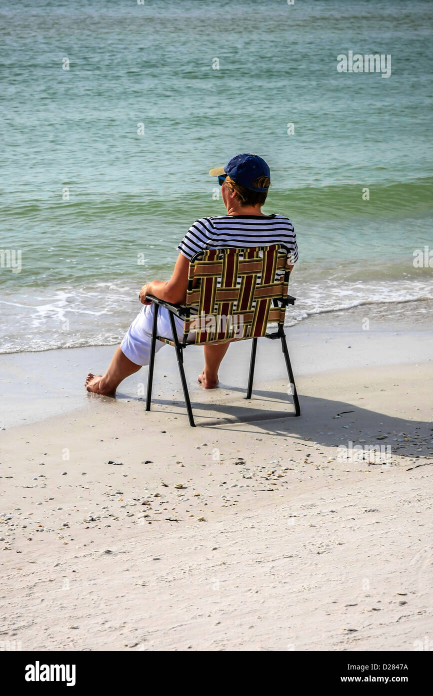 Eine Frau sitzt am Rand Wassers auf Siesta Key Beach im sonnigen Florida Stockfoto