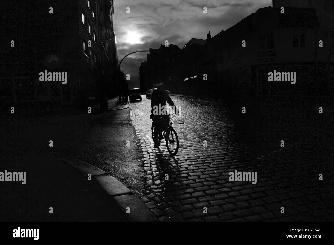 HAMBURG, Deutschland, 2. Januar 2013: Ein Radfahrer fährt auf einer Straße mit Kopfsteinpflaster in Hamburg St. Pauli Nachbarschaft. Stockfoto