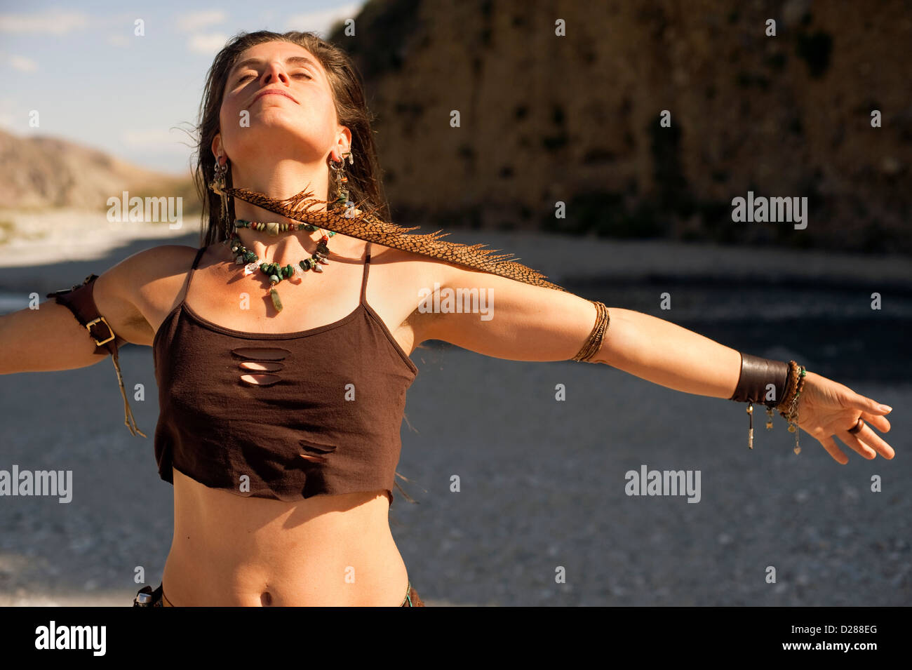 Frau mit Arm verbreiten breite tragen eine lange Feder Ohrringe an einem einsamen Fluss. Stockfoto Frau mit Arm verbreiten breite tragen eine lange Feder Ohrringe an einem einsamen Fluss. Stockfoto