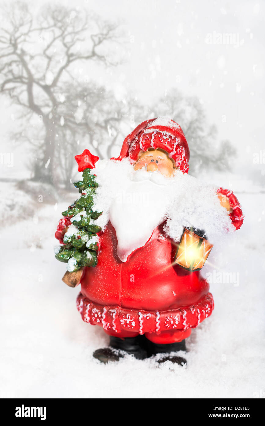 Weihnachtsmann mit leuchtende Laterne in verschneiter Winterlandschaft Stockfoto