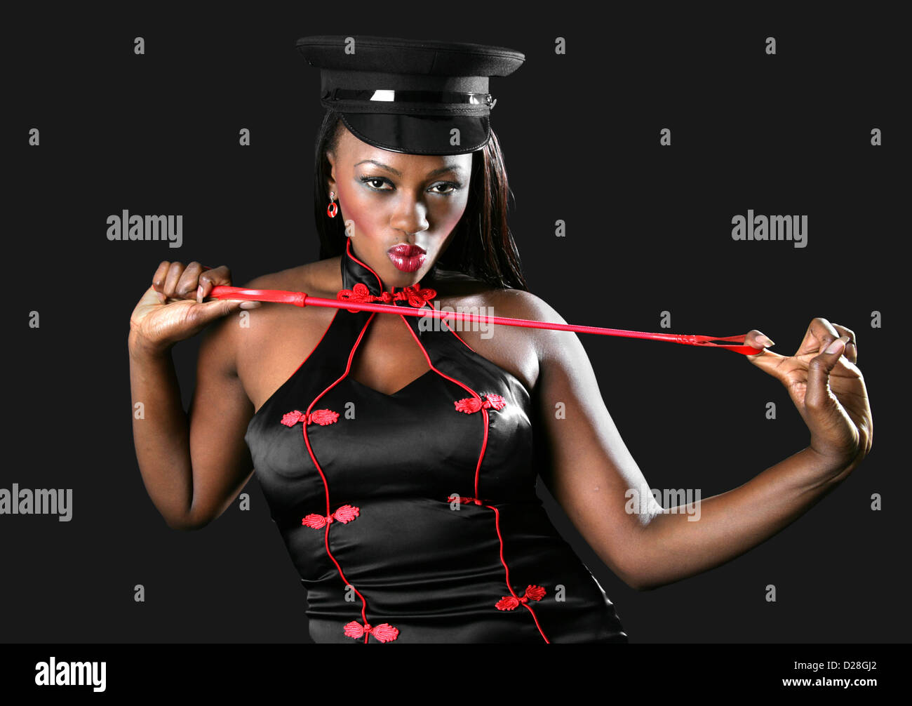 Schwarze afrikanische Frau trägt eine schwarze und rote chinesische Kleid, schwarze Kappe und ein rotes Reitgerte schwingt. Stockfoto