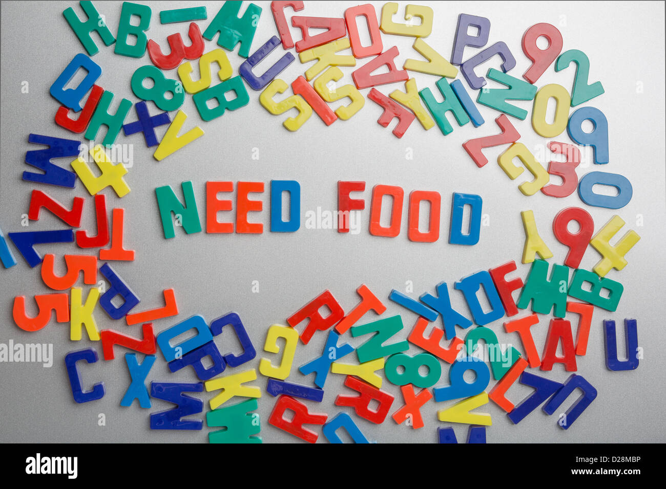 "Brauchen Nahrung"-Kühlschrank-Magnete buchstabieren Nachrichten aus einem Durcheinander von Buchstaben Stockfoto