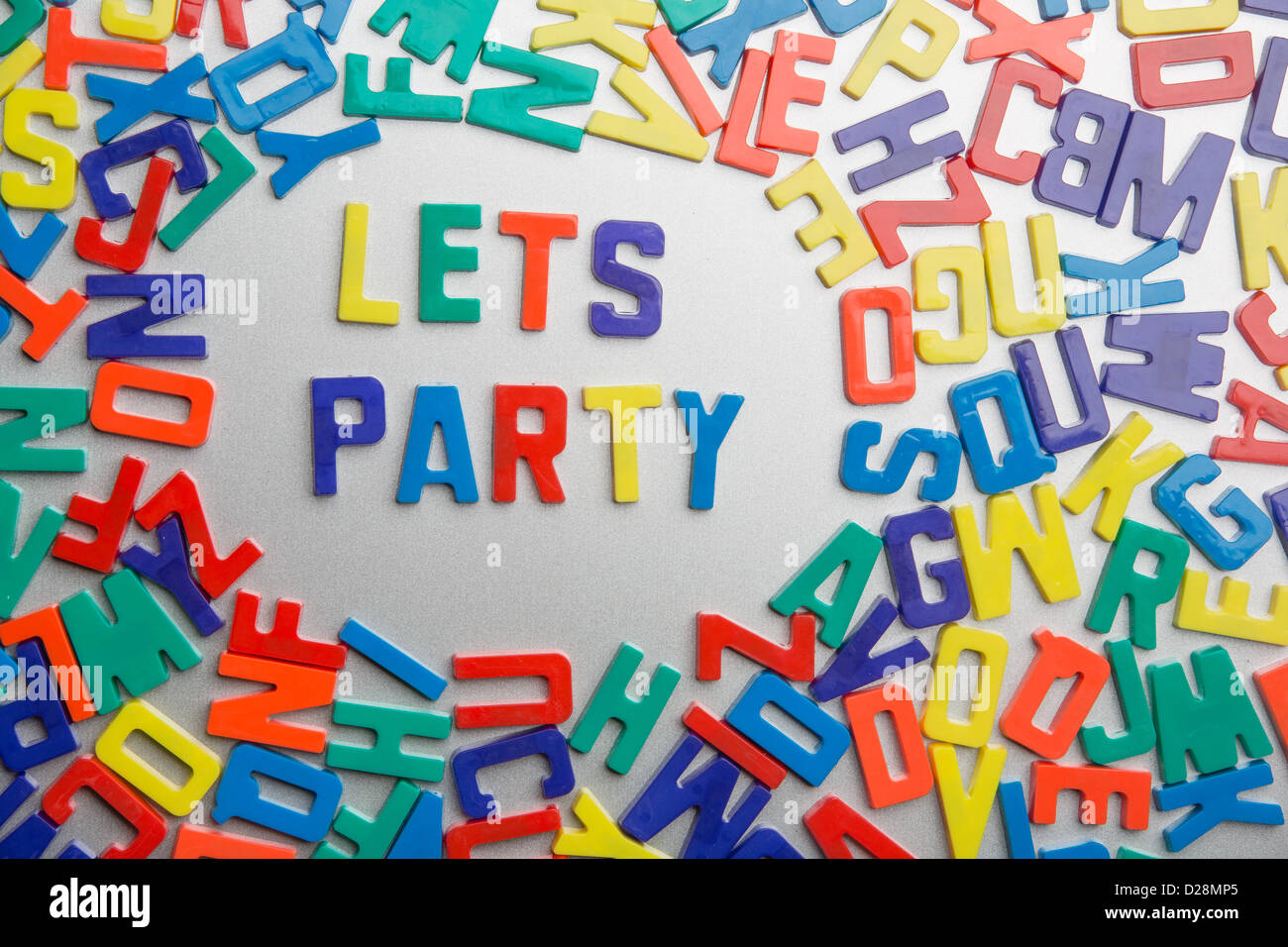 "Lets Party"-Kühlschrank-Magnete buchstabieren eine Nachricht aus einem Durcheinander von Buchstaben Stockfoto