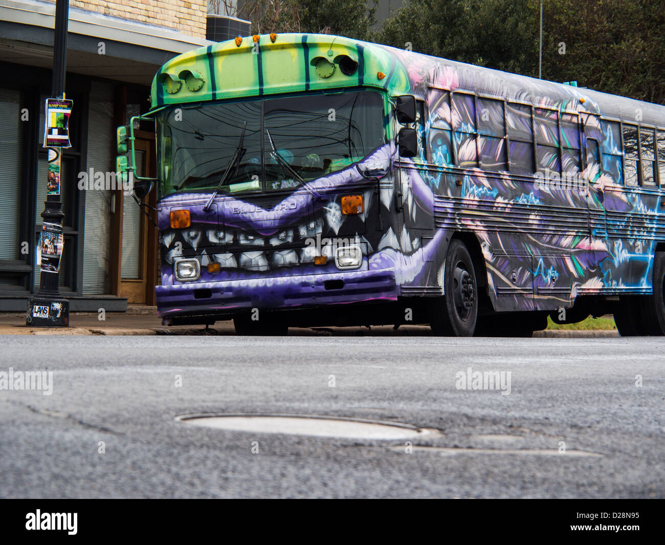 Lila und grüne Graffiti Schulbus mit Monster Backen gemalt auf der Seite, sitzend auf einer Ost-Austin-Straße Stockfoto
