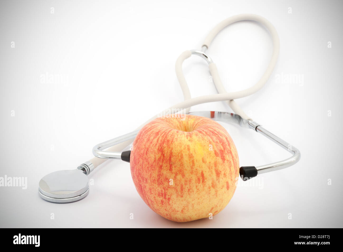 Mittels Stethoskop, einen Apfel auf weißem Hintergrund zu prüfen Stockfoto