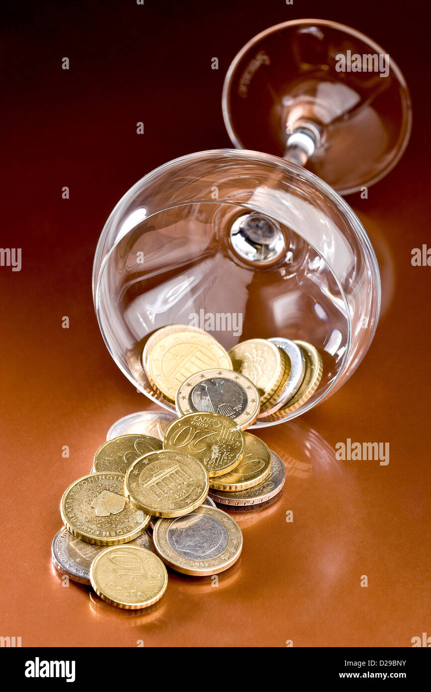 Liegende Glas und ein Haufen Münzen og Stockfoto