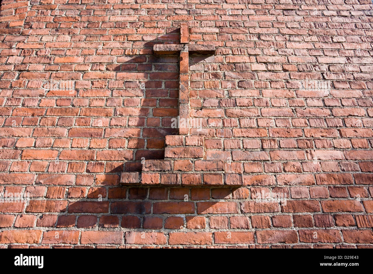 Christliches Kreuz auf roten Backsteinmauer Stockfoto