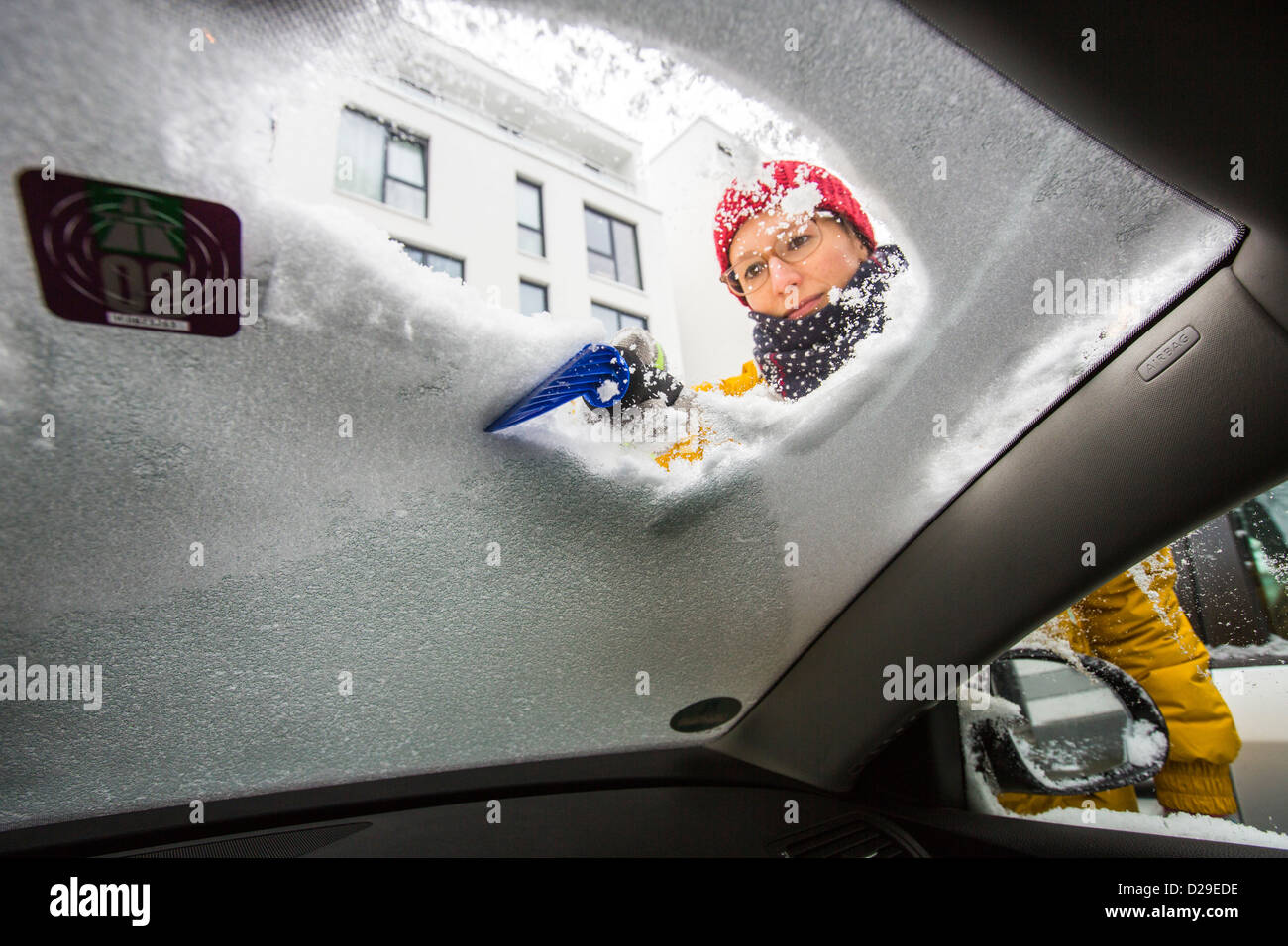 Frau reinigt ihr Auto von Eis und Schnee. Stockfoto