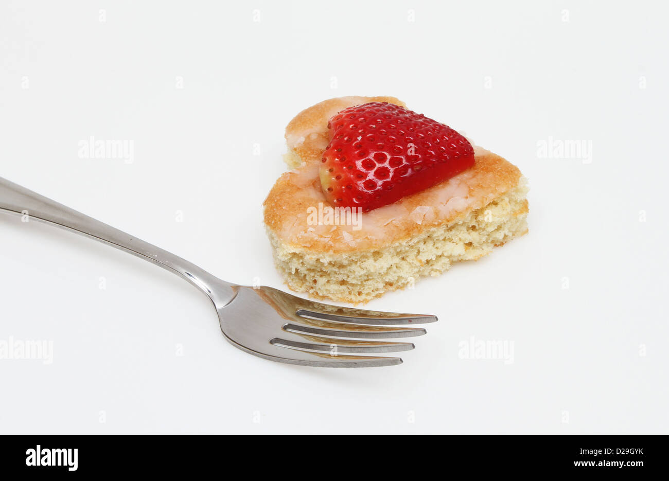 Nahaufnahme eines Herzens geformte Kuchen und Erdbeeren mit einer Gabel auf weißem Hintergrund Stockfoto