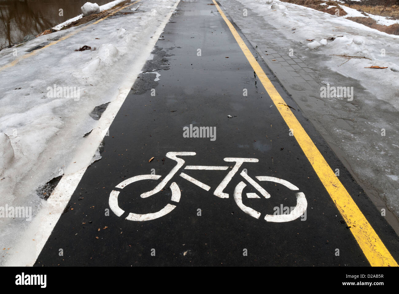 außerhalb der Saison auf nassen Fahrradweg mit Schnee und Eis von beiden Seiten Stockfoto