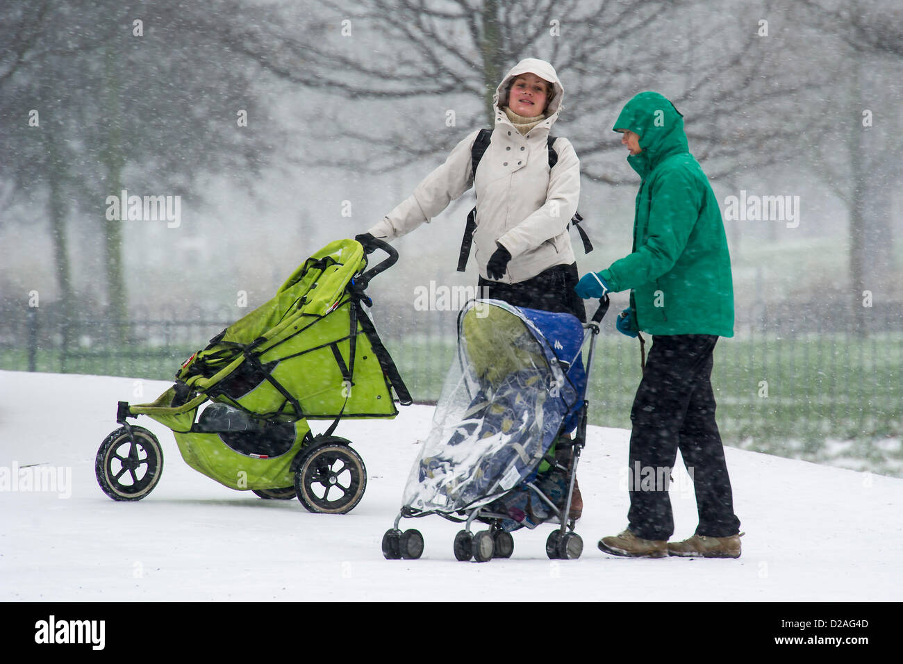 Schneefall macht pendeln schwieriger aber hört nicht auf Dogwalkers oder Mütter ihre kleinen Kinder auf Clapham Common, London, UK, 18. Januar 2013 herausnehmen. Stockfoto