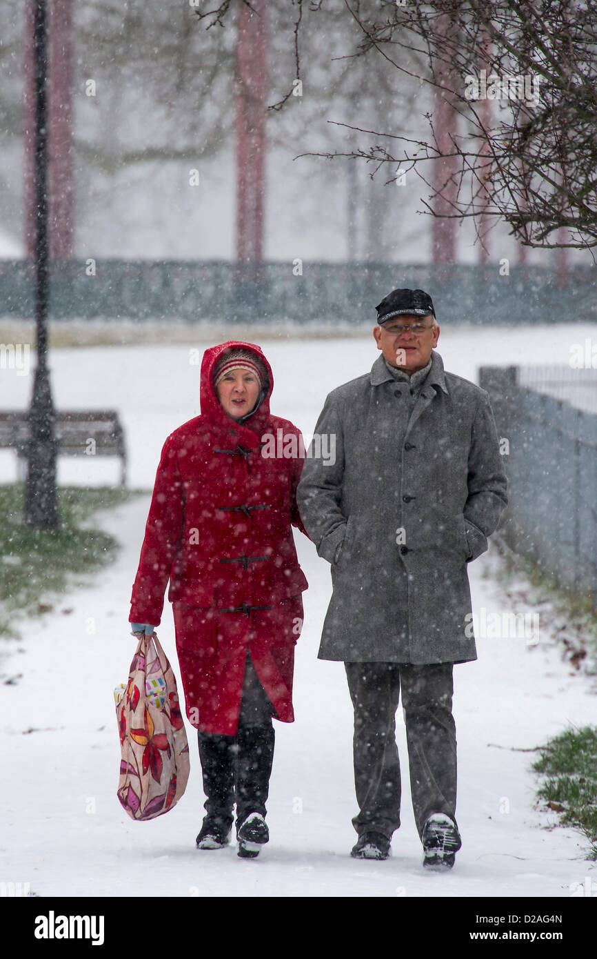 Ein deutsches Ehepaar Besuch bei ihrer Familie in London sind vom Wetter überrascht. Schneefall macht pendeln schwieriger aber hört nicht auf Dogwalkers oder Mütter ihre kleinen Kinder auf Clapham Common, London, UK, 18. Januar 2013 herausnehmen. Stockfoto