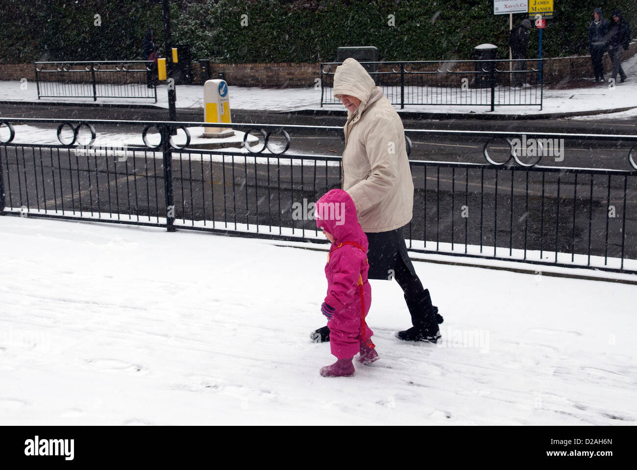 Frau, die helfen, eines kleinen Kindes in ein rosa Schneeanzug Stockfoto