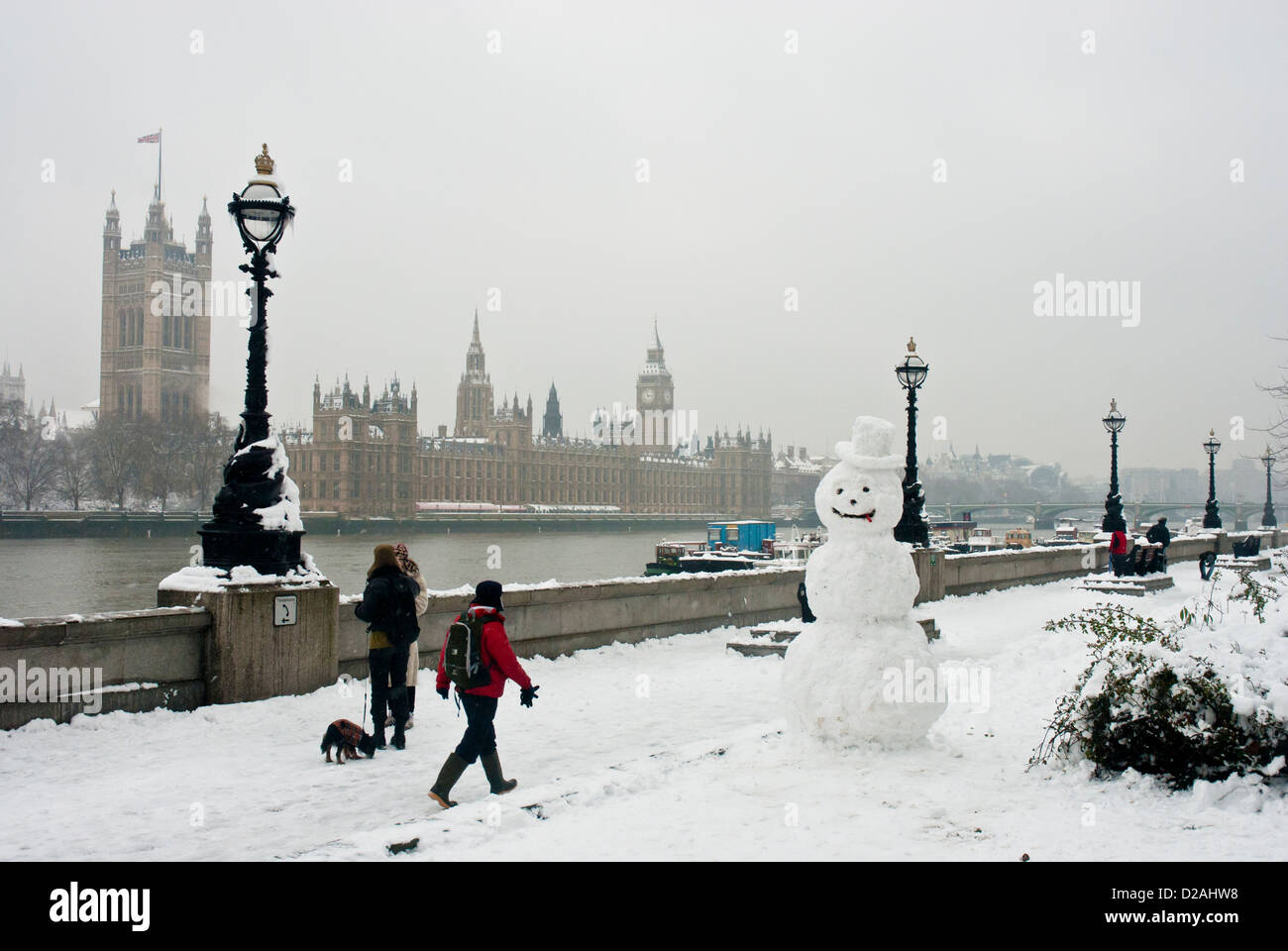 London, im Winter mit Schnee und Schneemann im Vordergrund und der Themse und dem Parlament. Stockfoto