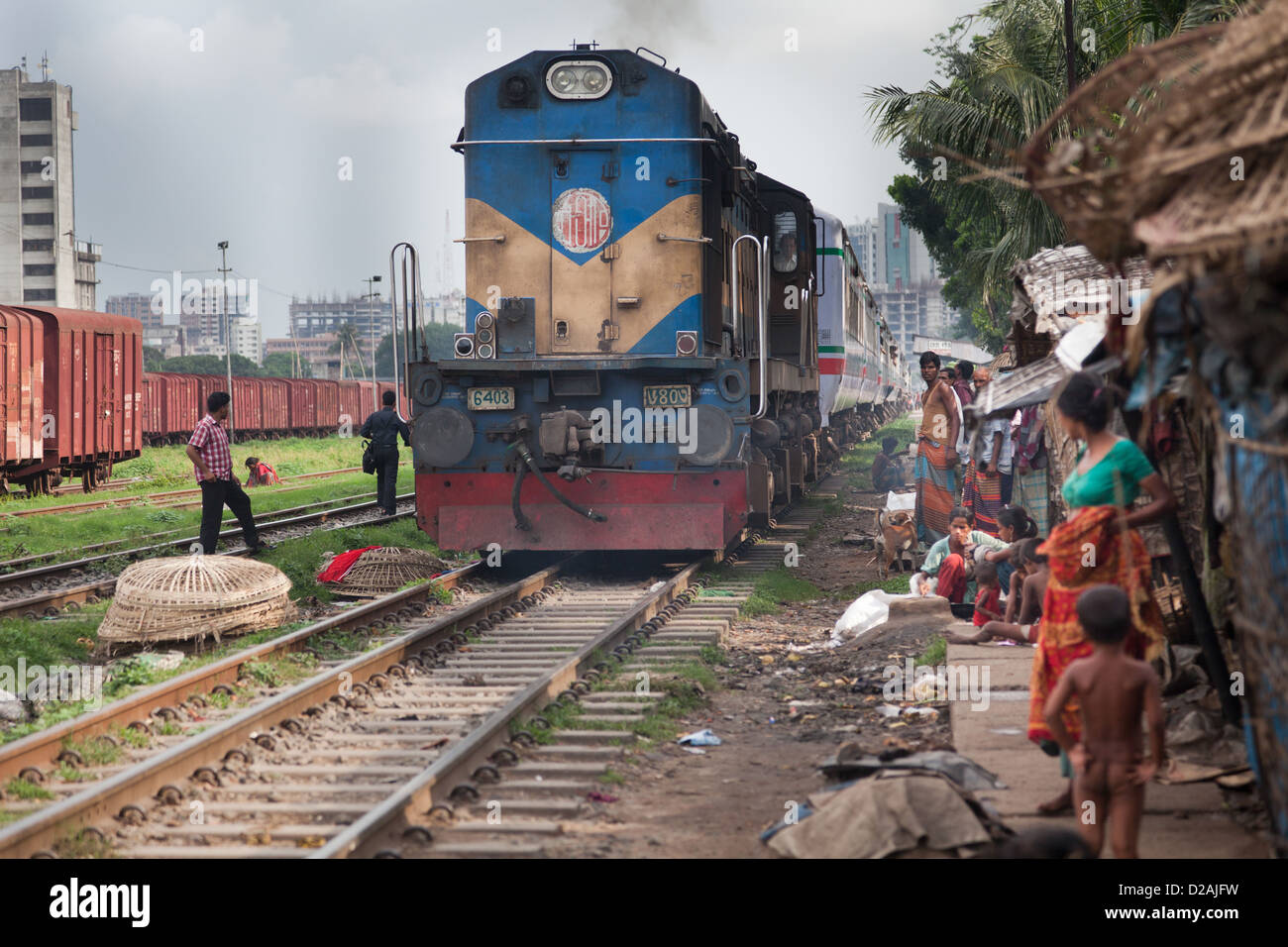Ein weiterer Zug übergibt den Slum Tejgaon, an die Slums und spielende Kinder. Stockfoto
