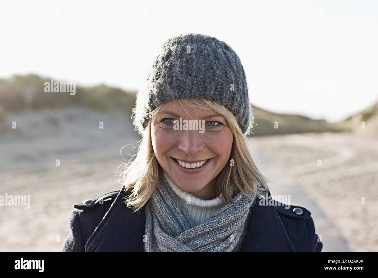 Lächelnde Frau zu Fuß am Strand Stockfoto