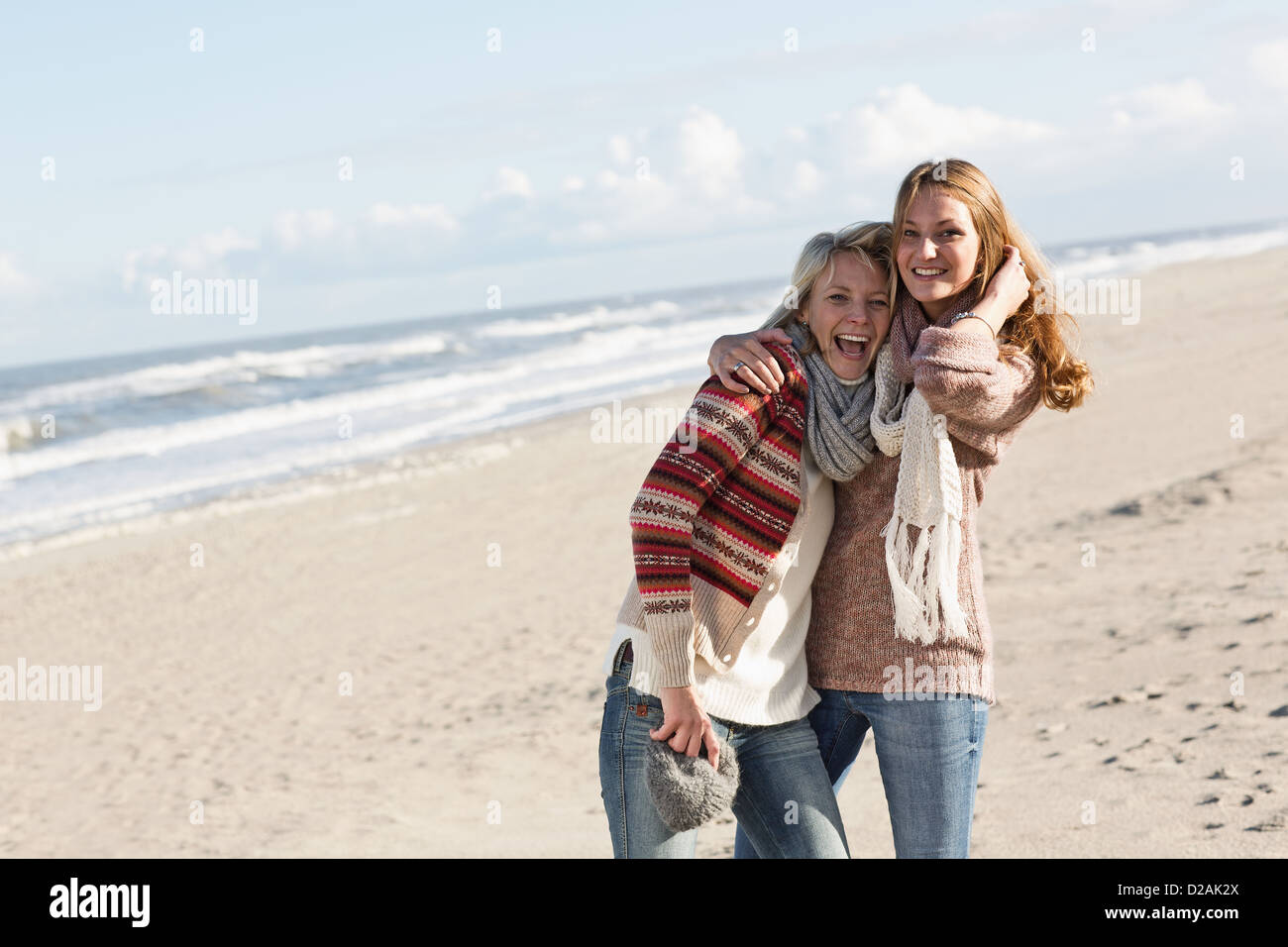 Lächelnde Frauen umarmen am Strand Stockfoto