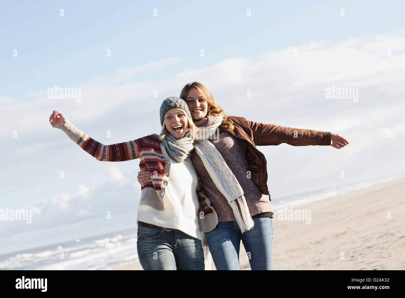 Lächelnde Frauen umarmen am Strand Stockfoto