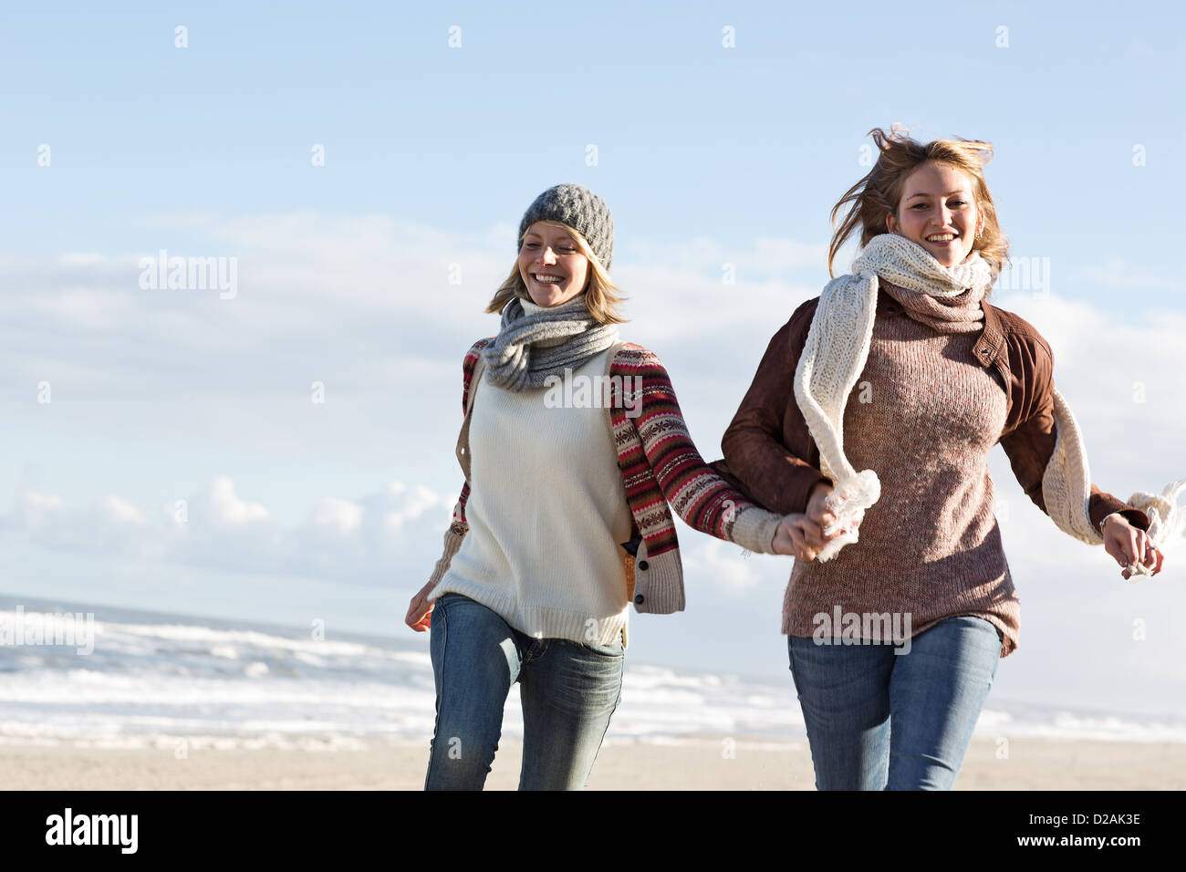 Lächelnde Frauen laufen am Strand Stockfoto
