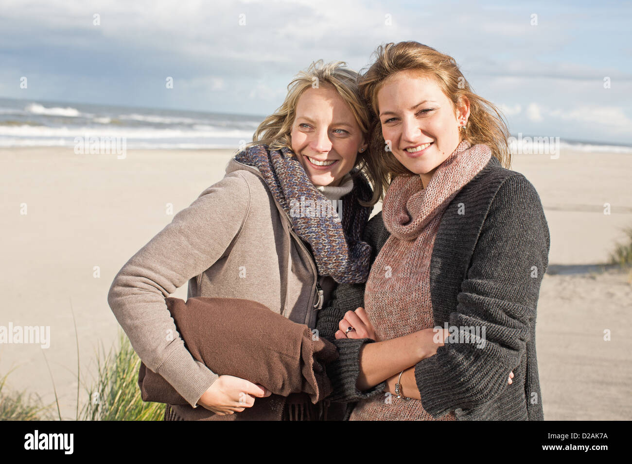 Lächelnde Frauen stehen am Strand Stockfoto