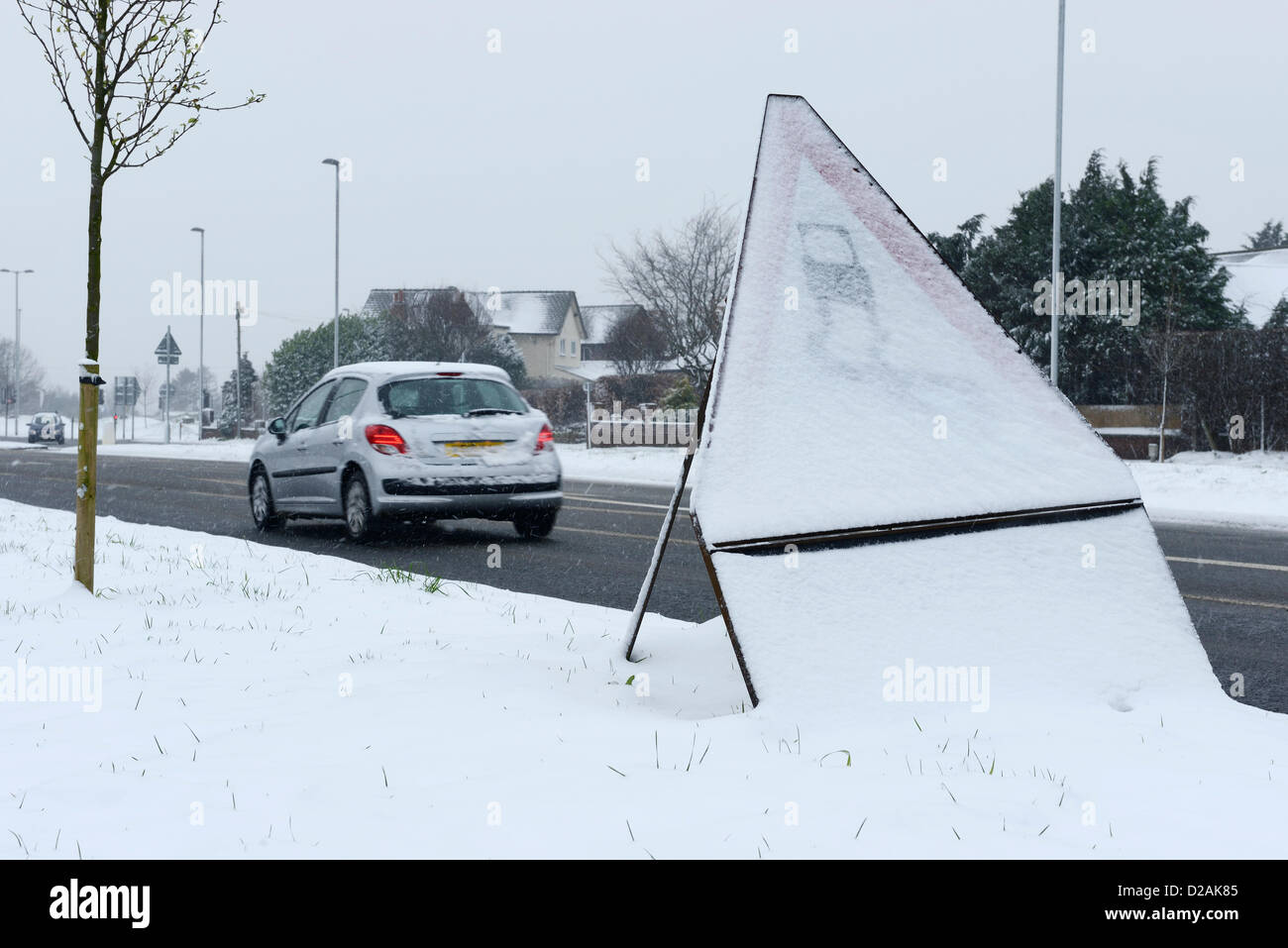 Chester UK. 18. Januar 2013. Ein Auto fährt Vergangenheit einen Schild Warnung vor rutschigen Straßenverhältnissen schneebedeckten. Stockfoto