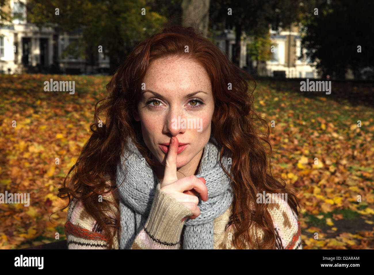 Frau, die Finger über die Lippen im park Stockfoto