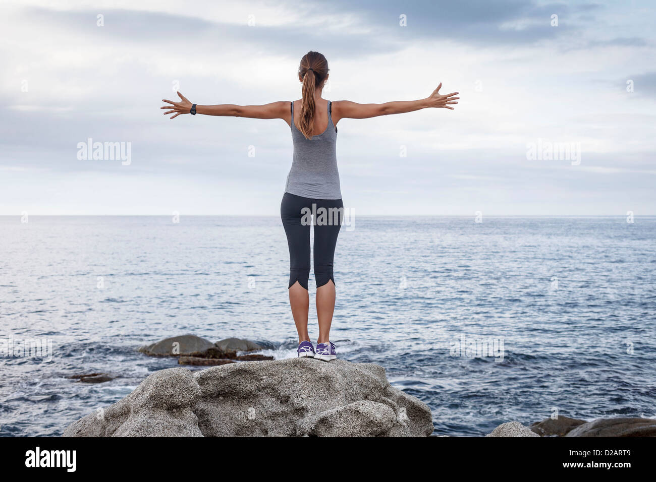 Frau auf Felsen mit Blick auf Meer Stockfoto