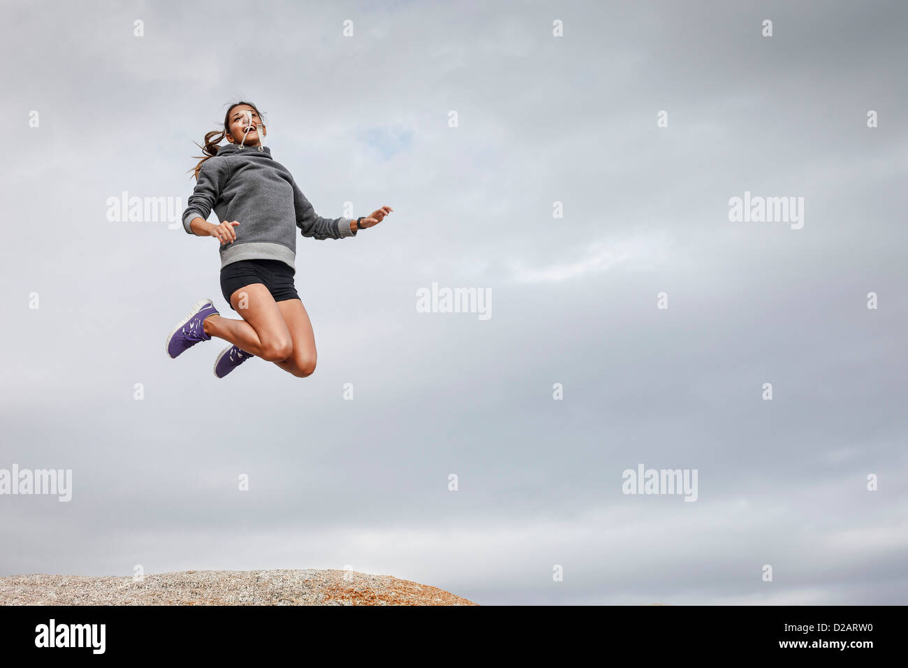 Frau springen vor Freude auf Findling Stockfoto