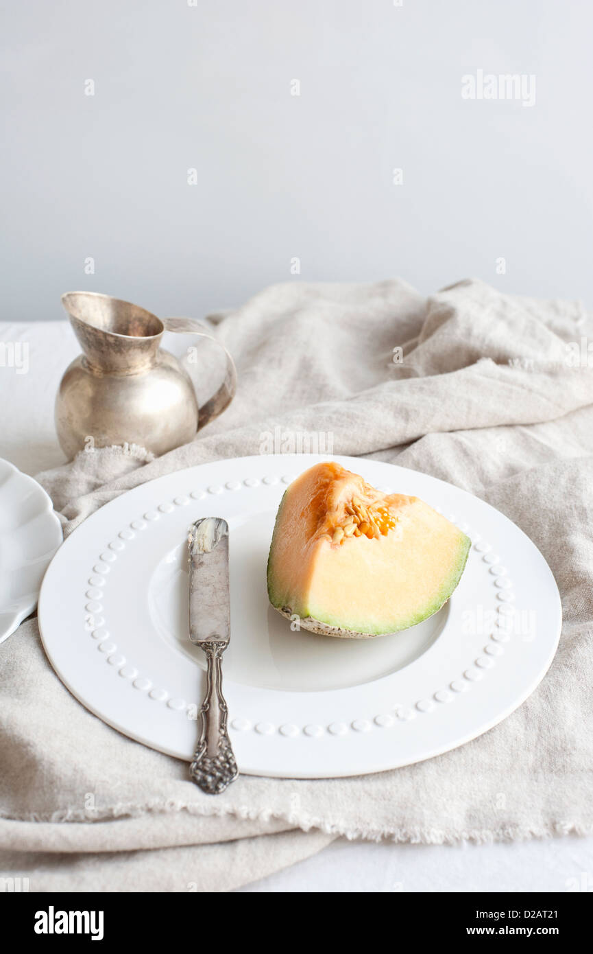 Teller mit Melone mit Buttermesser Stockfoto
