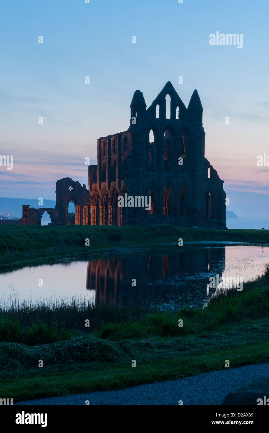 Whitby Abbey Silhouette & im Abendlicht (historische Ruinen & roten Sonnenuntergang Himmel im Wasser der Teich wider, North Yorkshire, England, Großbritannien beleuchtet. Stockfoto