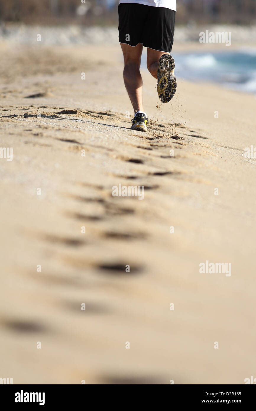 Mann mit Muskeln Beine laufen auf dem Sand des Strandes Stockfoto