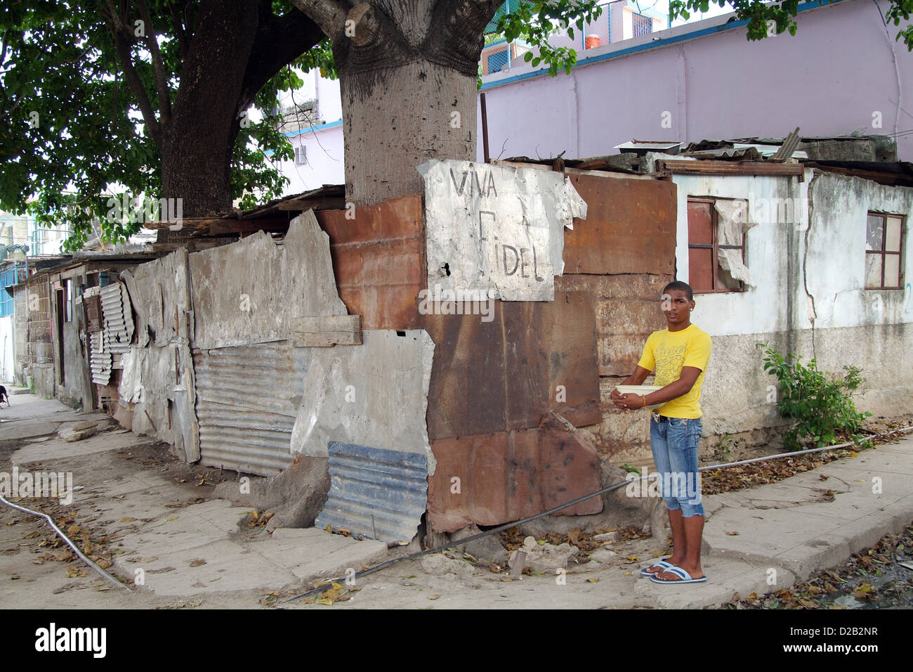 Havanna, Kuba, steht ein junger Mann an einer Straßenecke vor dem Motto Viva Fidel Stockfoto