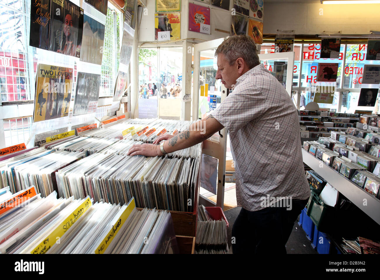 Mann sucht durch eine große Schachtel mit LP in einem Plattenladen in Brighton, East Sussex, UK. Stockfoto