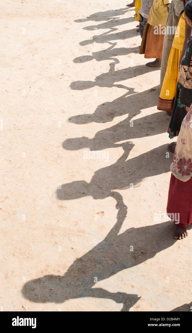 Schatten des indischen Dorfkinder in einer Linie, die Hand in Hand spielen. Andhra Pradesh, Indien Stockfoto