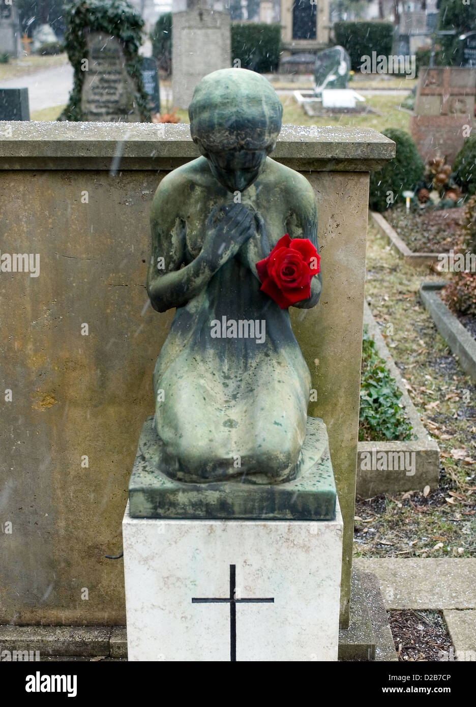 Freiburg, Deutschland, eine trauernde schwere Figur mit rote Rose auf dem Friedhof Stockfoto