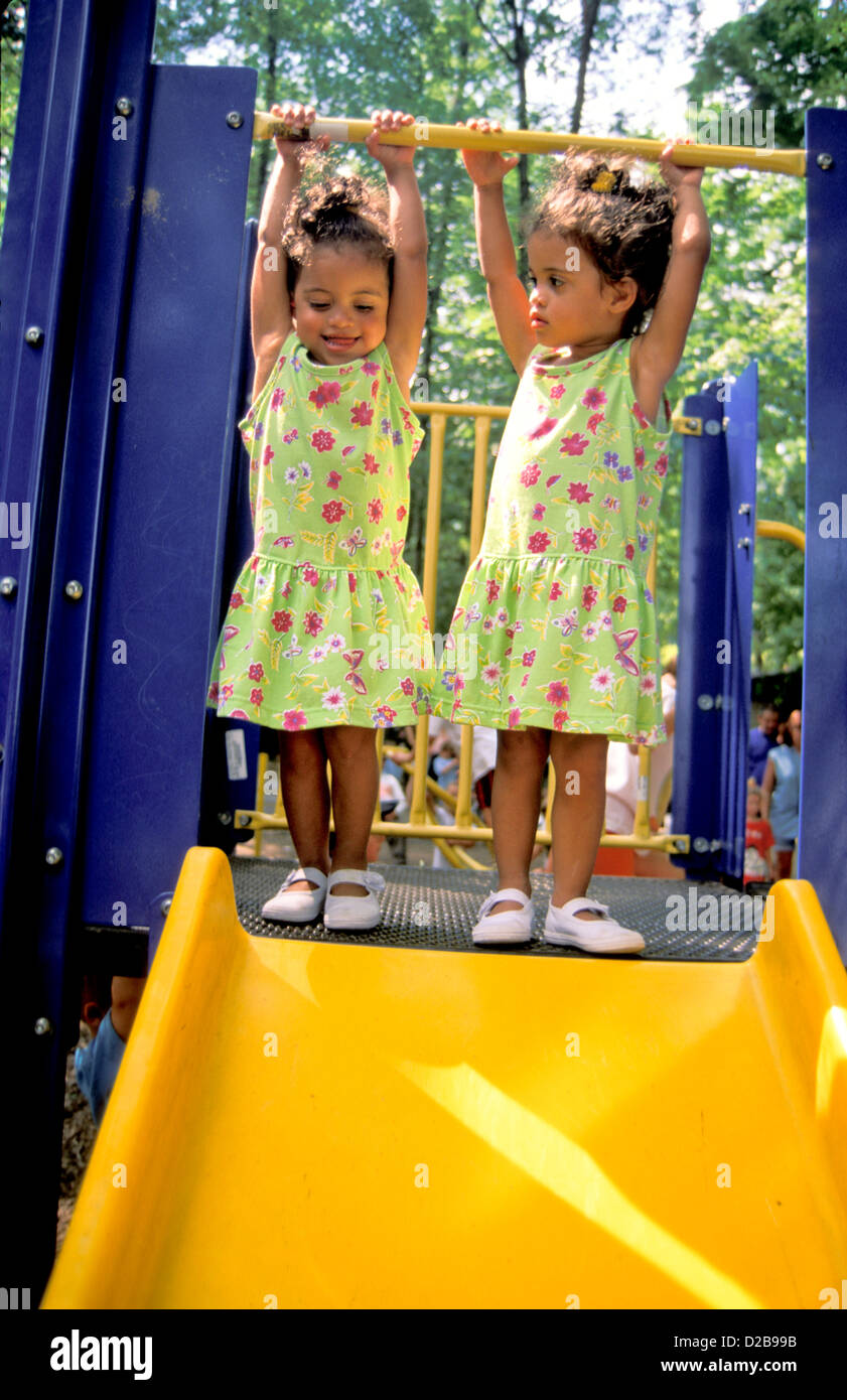Zwillingsmädchen In identischen Outfits, stehen an der Spitze der Folie Stockfoto