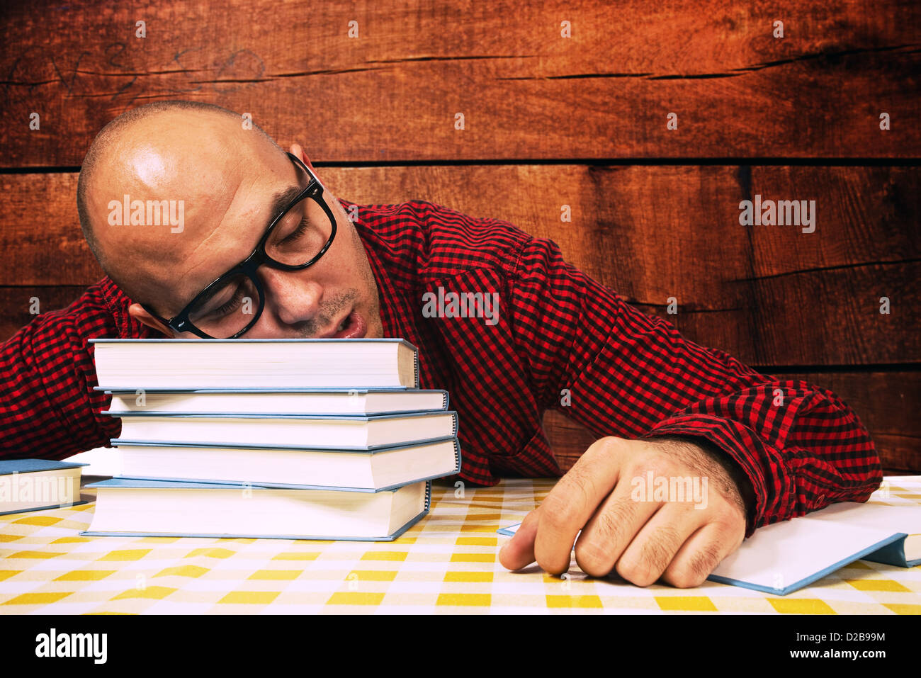 Junge Erwachsene Fett Schüler schlafen auf einem Stapel Bücher auf dem Tisch. Stockfoto