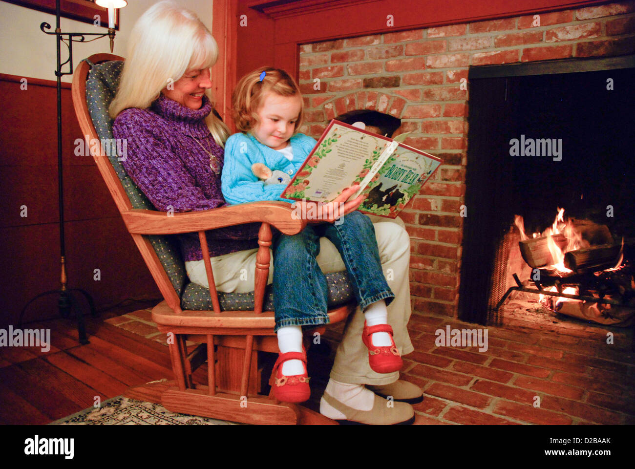 5 Jahre altes Mädchen-Lesung mit Großmutter durch Feuer Stockfoto