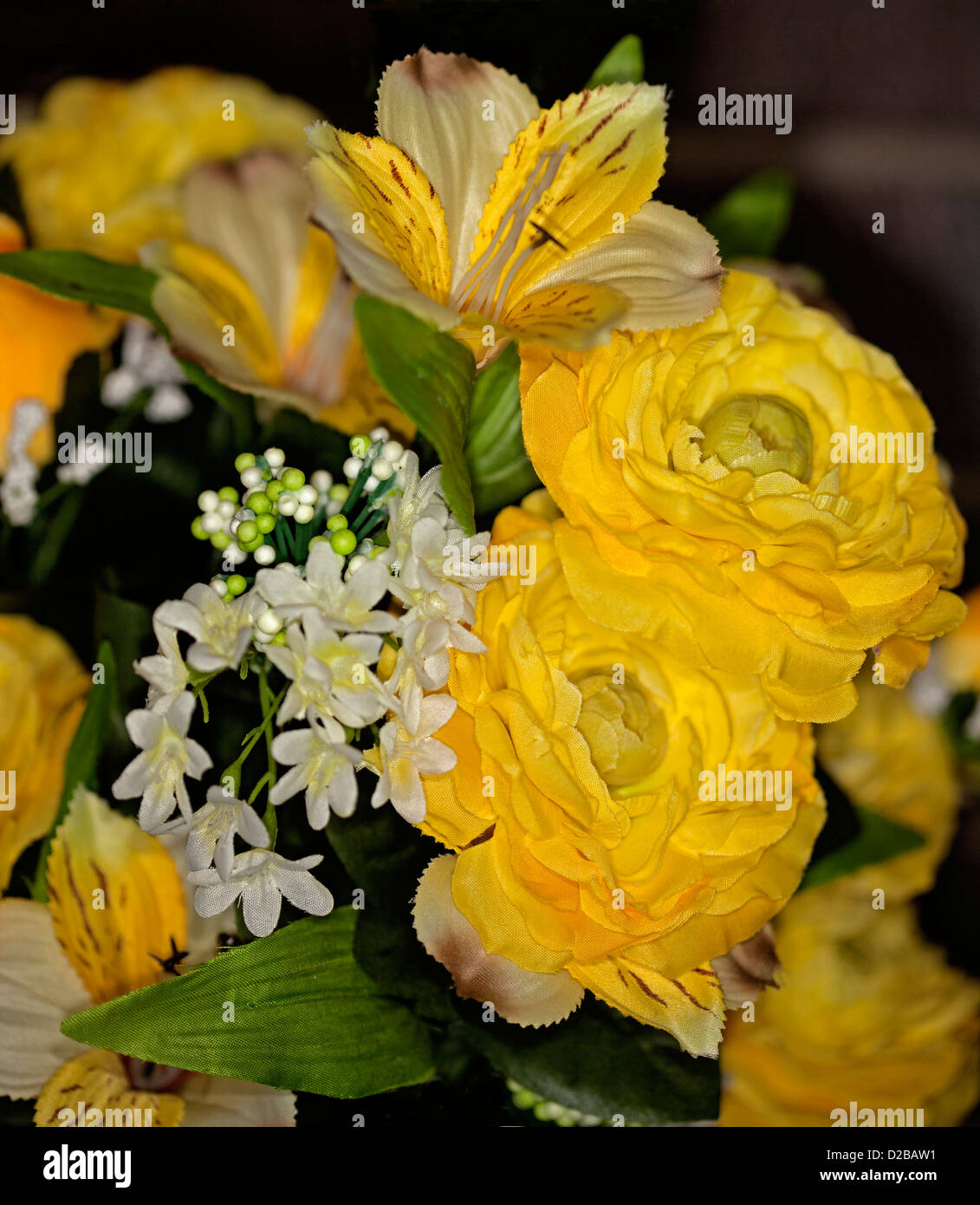 Bouquet von schönen künstlichen / Seide Rosen und andere Blumen - leuchtend gelb und weiß - vor einem dunklen Hintergrund Stockfoto