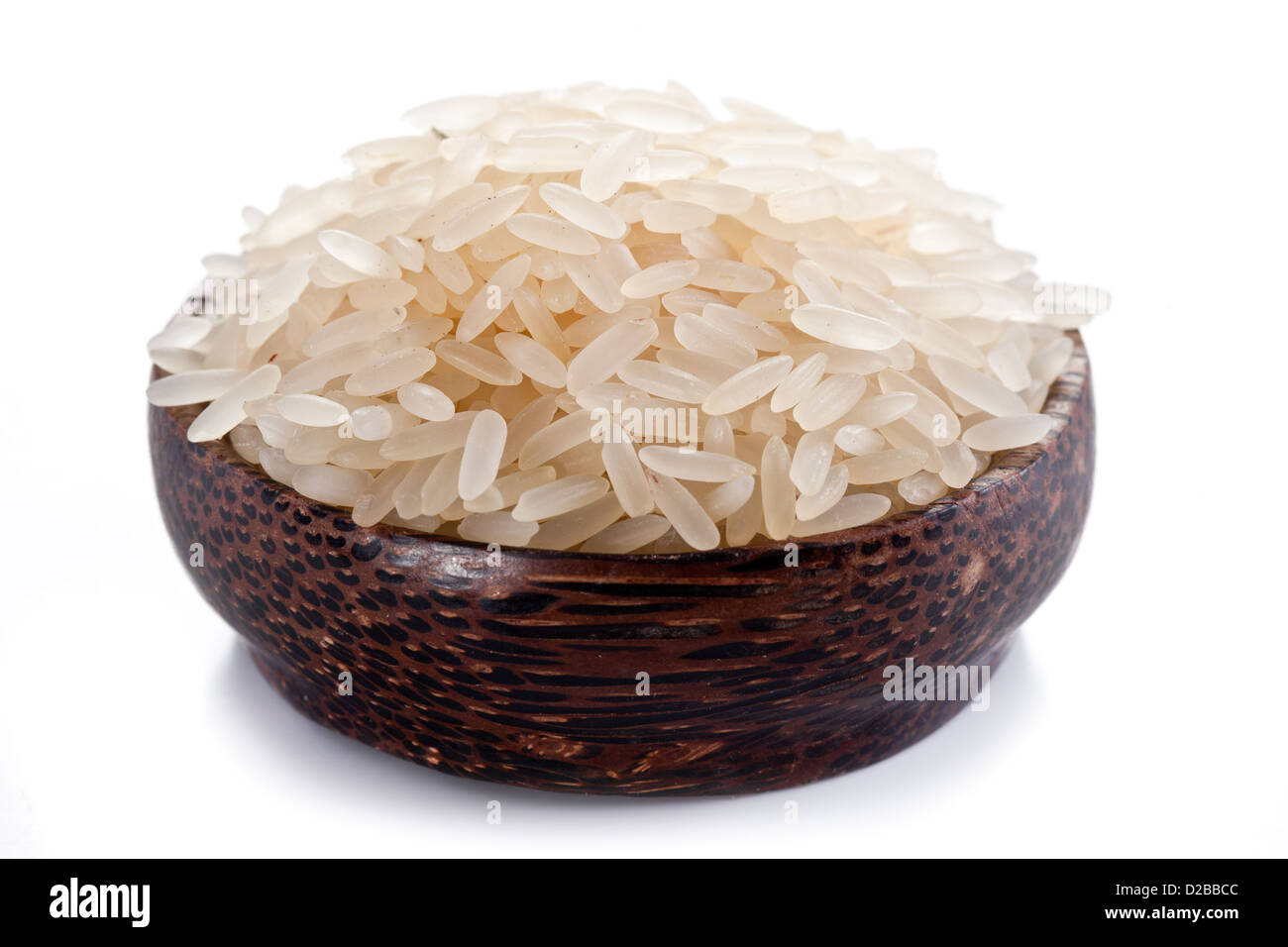 Ungekochten Reis in einer Holzschale auf weißem Hintergrund. Stockfoto
