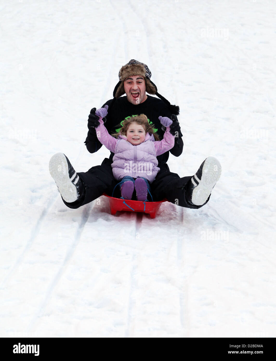 Vater und Tochter Spaß auf frischem Schnee Rodeln Stockfoto