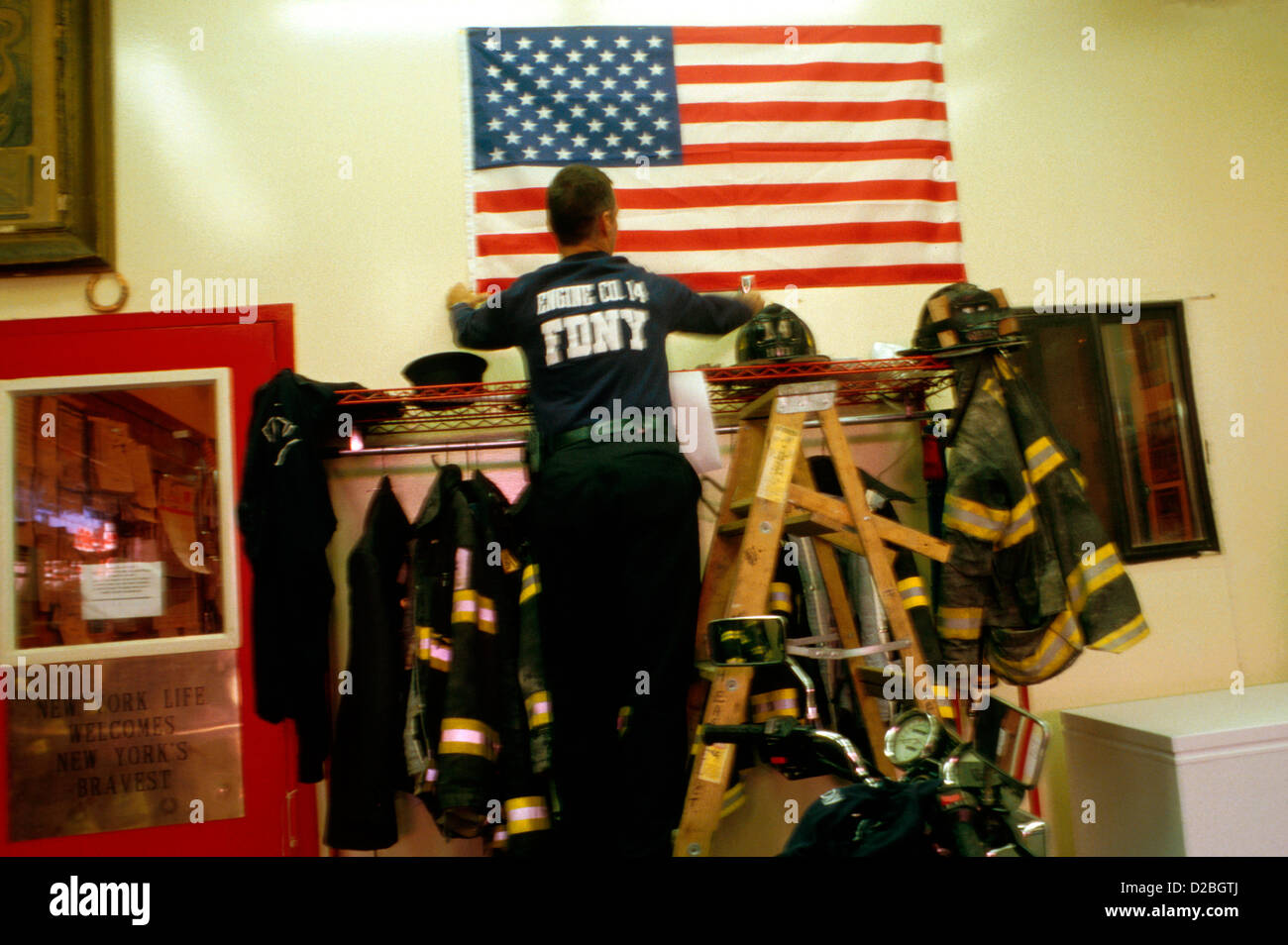 New York City, 11.09.2001. Inneren Feuerwache #14. Feuerwehrmann, die Übergabe der US-Flagge im folgenden World Trade Center-Angriff Stockfoto