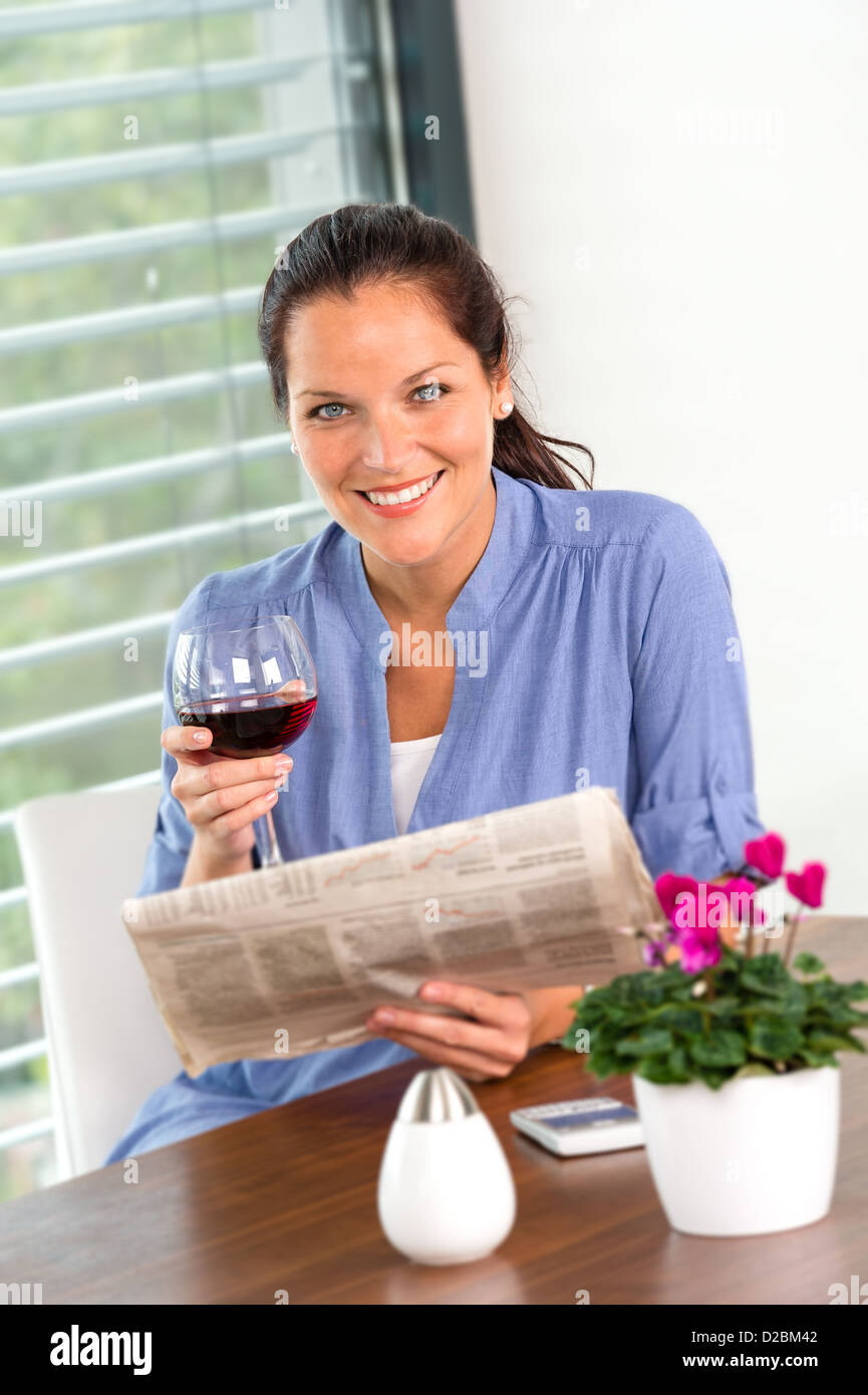 Fröhliche Frau, lesen, trinken Wein Zeitung Wohnzimmer Stockfoto