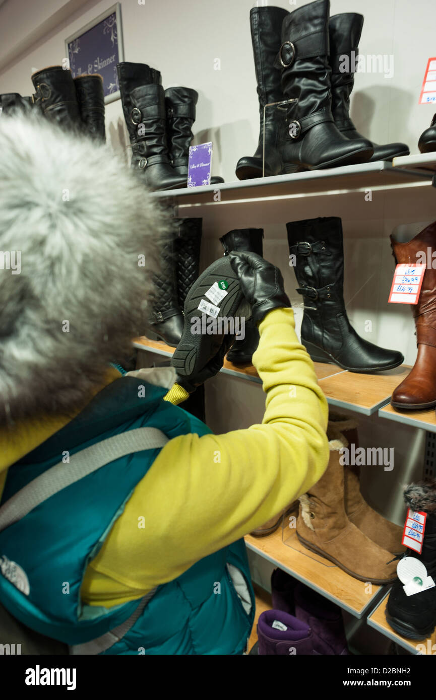 Frau auf der Suche zu Preisen von Stiefeln im Schuhgeschäft Stockfoto