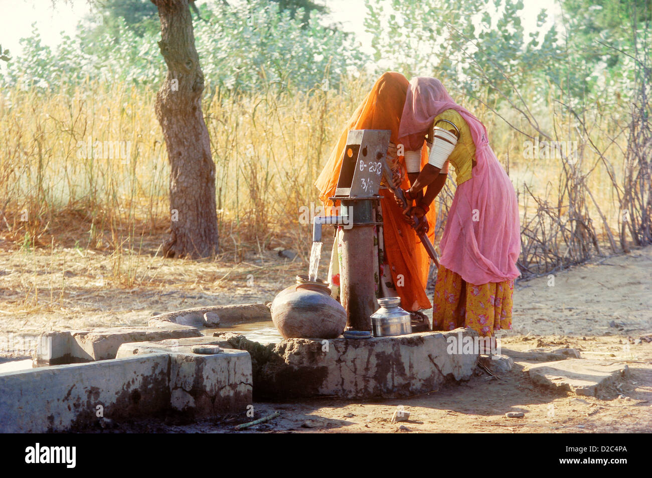 Frauen im Schleier Zeichnung Wasser aus einer Hand zu Pumpen. Westlichen Rajasthan, Indien. Stockfoto