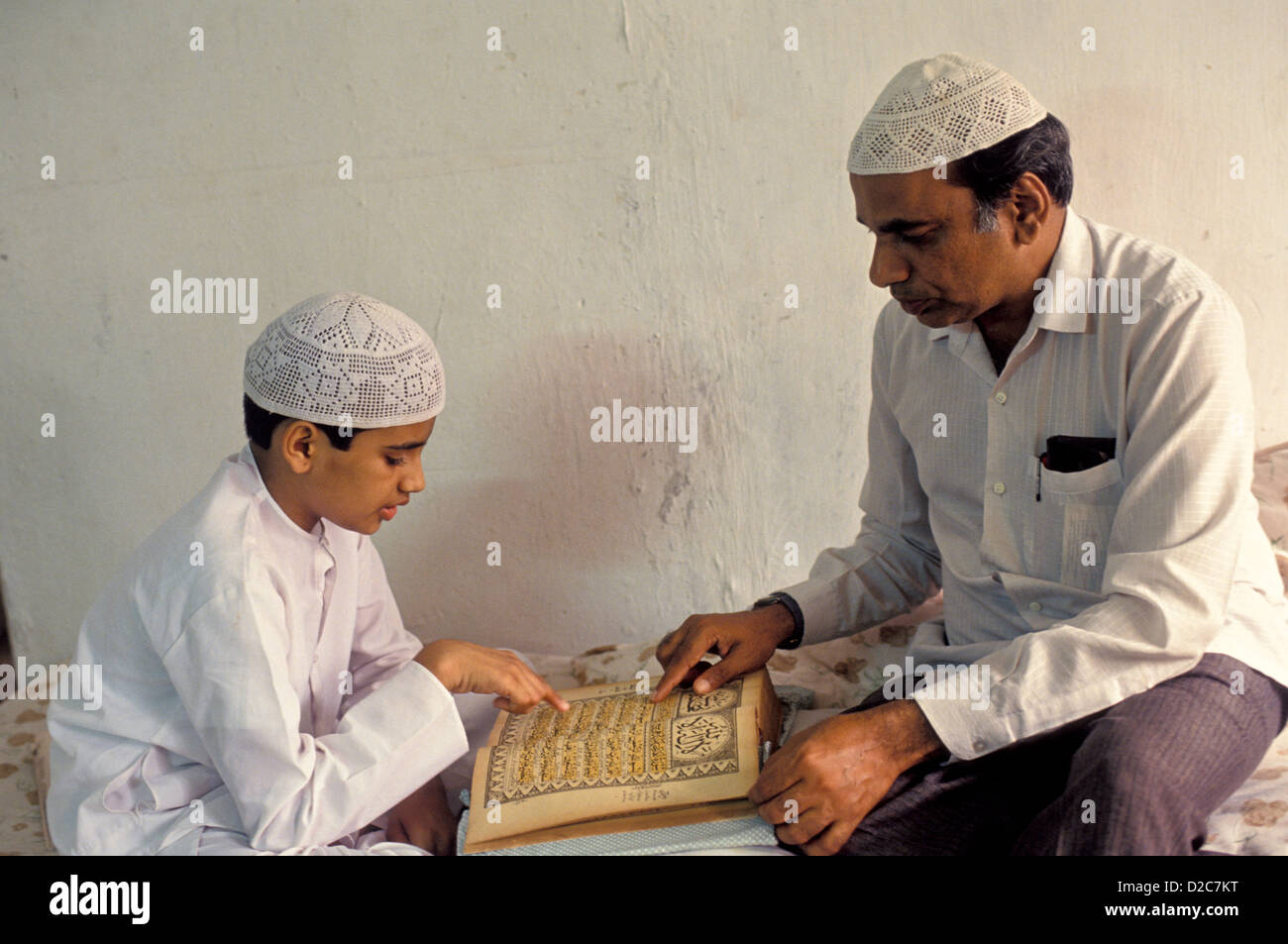 Indien. Muslimische jungen Heiligen Lesebuch mit Hilfe seines Vaters Stockfoto