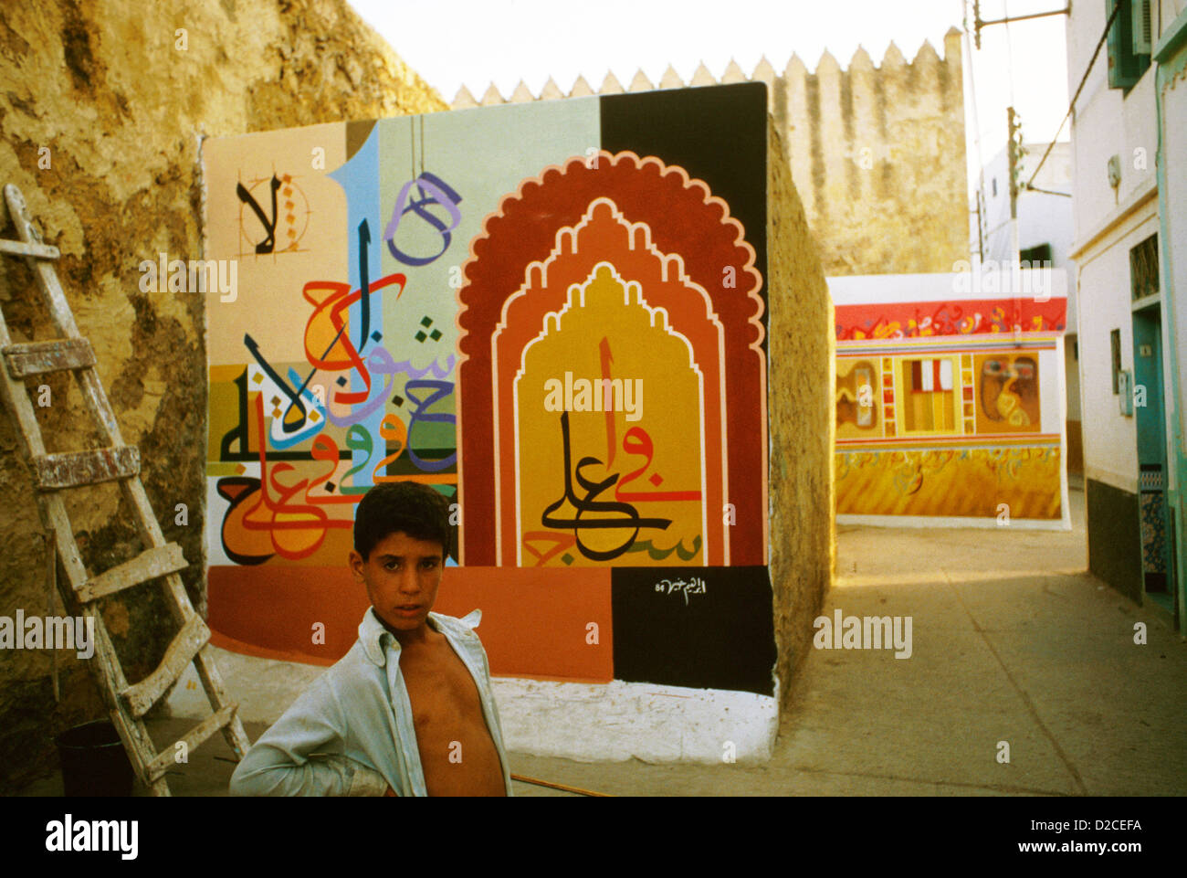 Marokko, Asilah. Junge vor Wandmalereien. Stockfoto