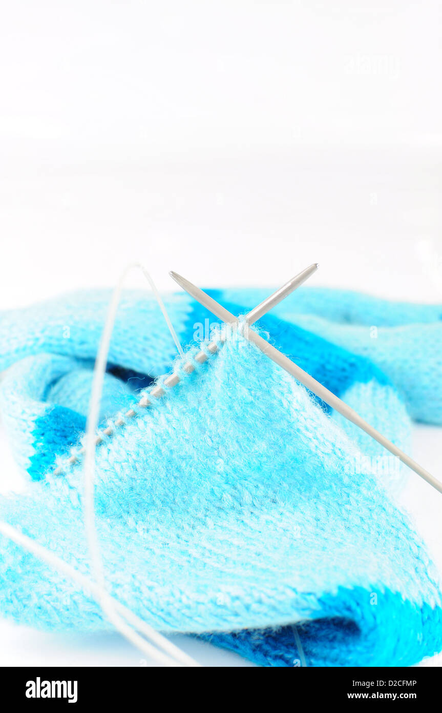 Nadeln stricken blauen Schal auf weißem Hintergrund Stockfoto